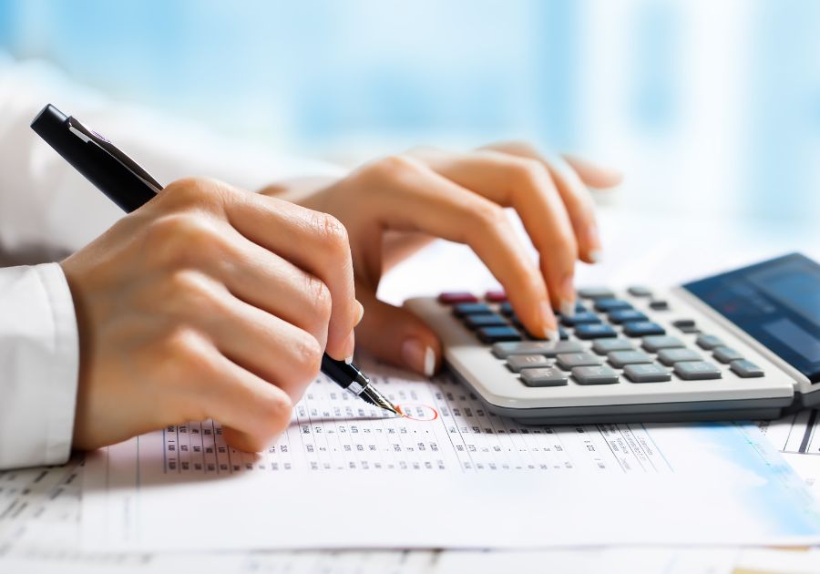 Lawyer Holding a Pen and Using a Calculator While Reviewing Accounting Documents